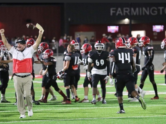 Coach celebrating as football players run off field