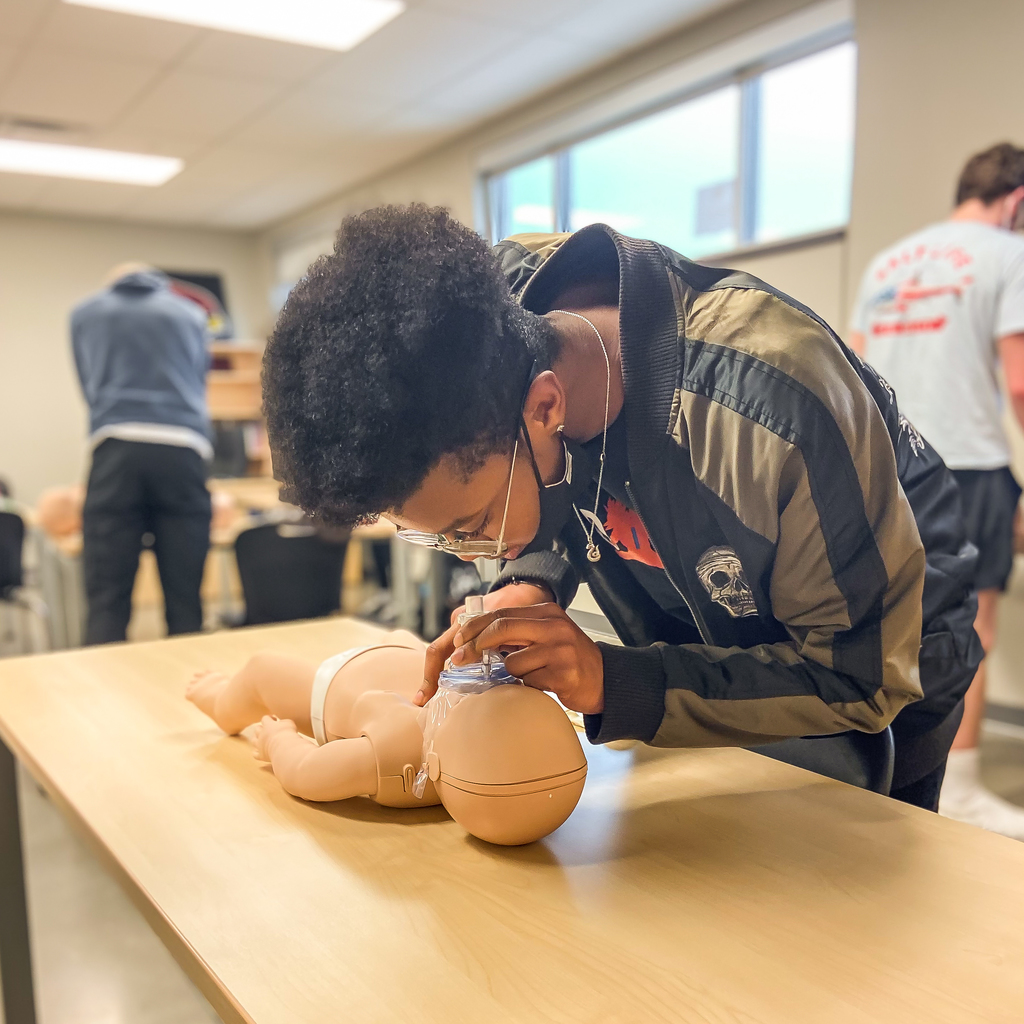 Student performing CPR on an infant dummy