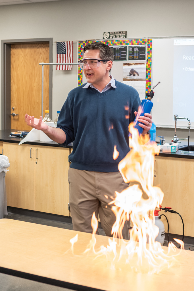 Mr. Jackson standing before a table alight with fire.