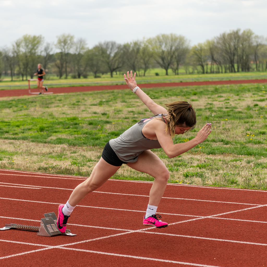 Student pushing off a starting block to sprint down the track