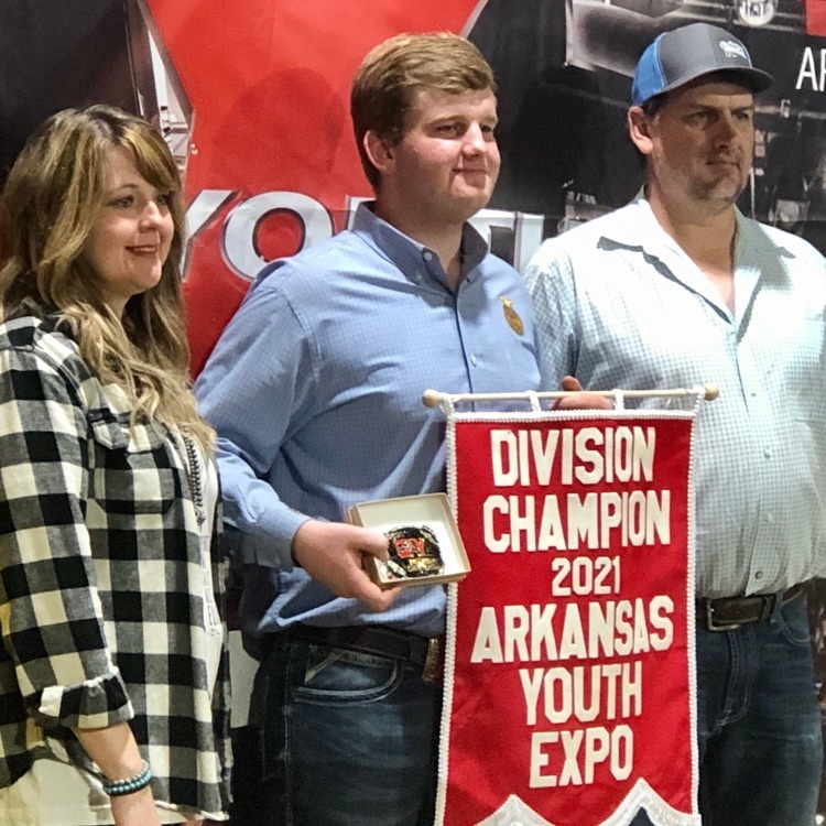 student holding a banner declaring his win standing alongside his parents