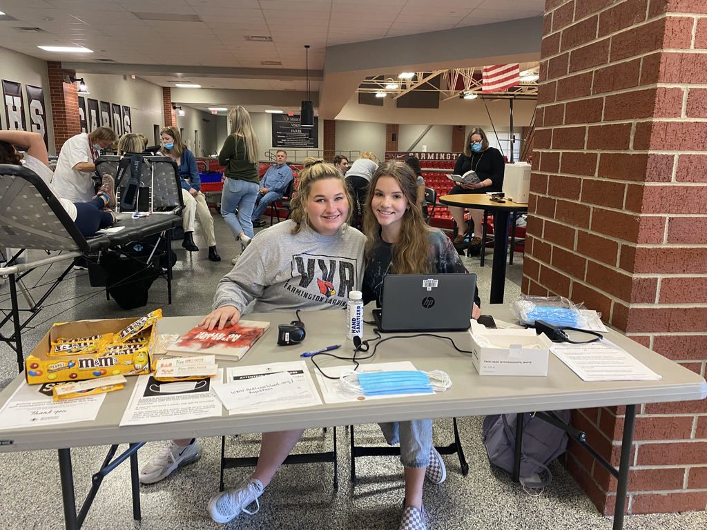 Two students sit at a desk welcoming those who check into the blood drive.