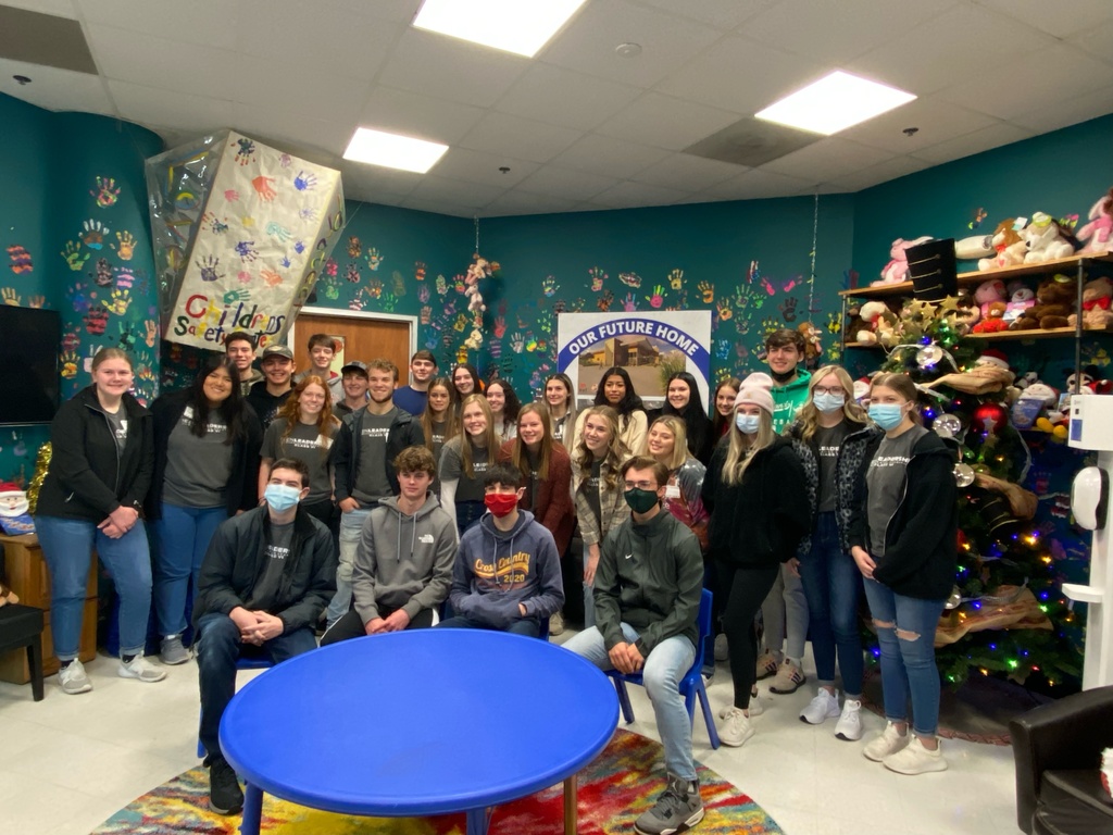 Roughly 30 students stand together posing in a room at the Child Safety Center