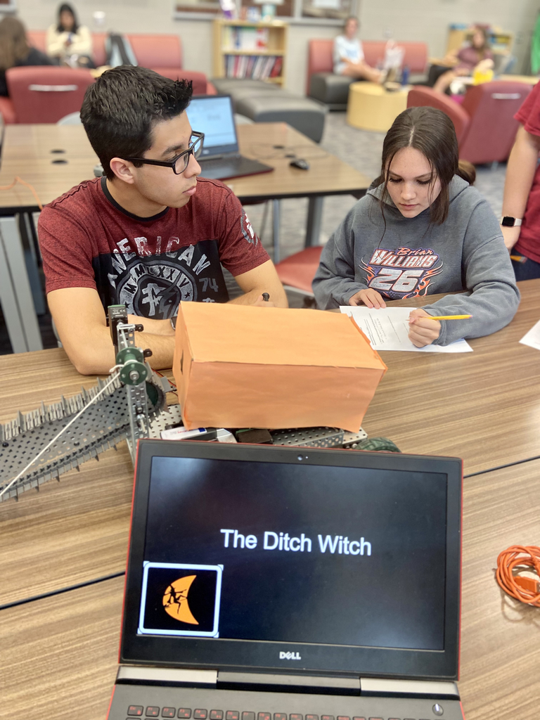 Robotics student & childcare student talking in the background of the picture. Foreground is a screen that says ditch witch & a robot.