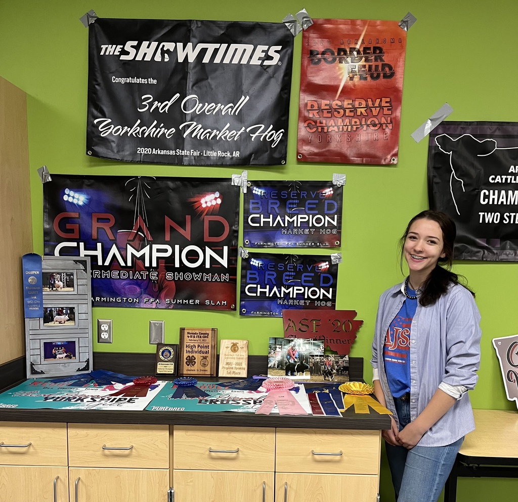 student standing in front of her champion banners from shows