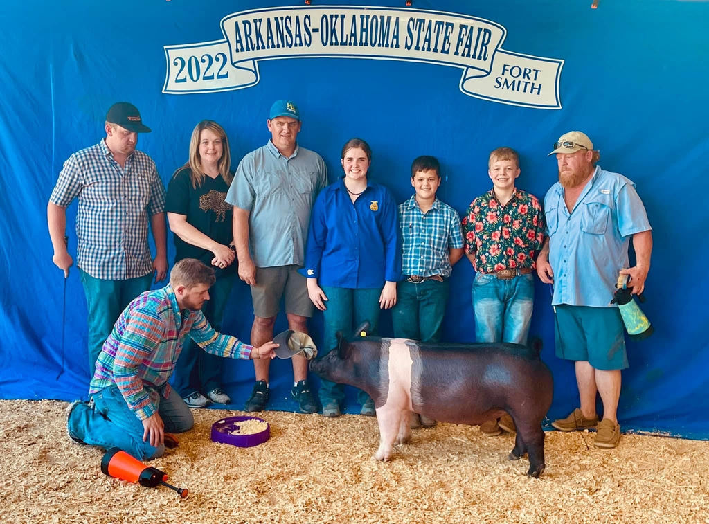 student posing with family members and hog