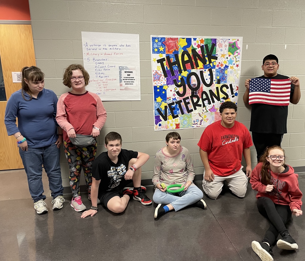 students posing in front of a thank you veterans banner