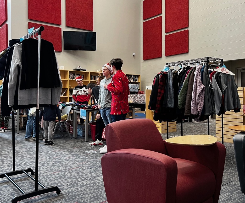 students standing in library with carts full of clothing