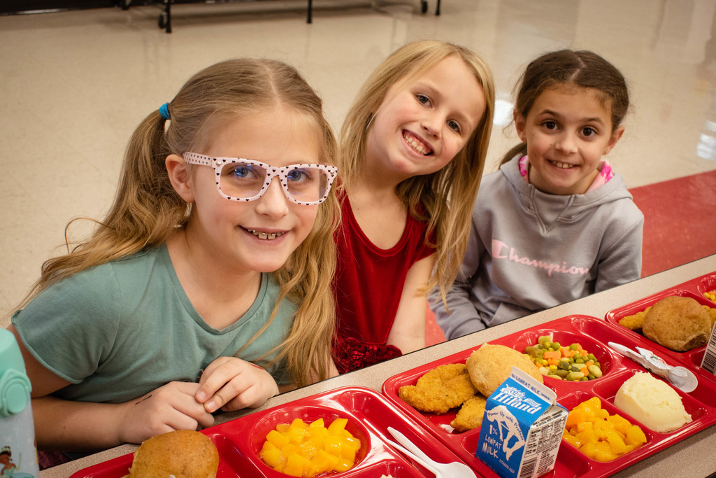3 students smiling with their lunch trays