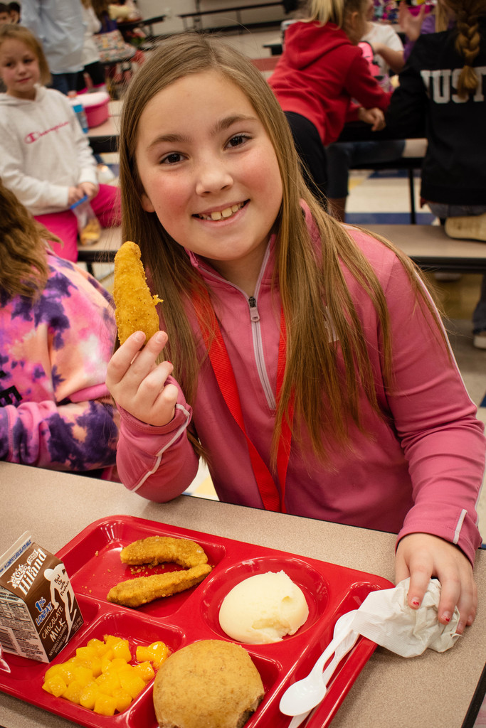 Student smiling, holding a chicken strip