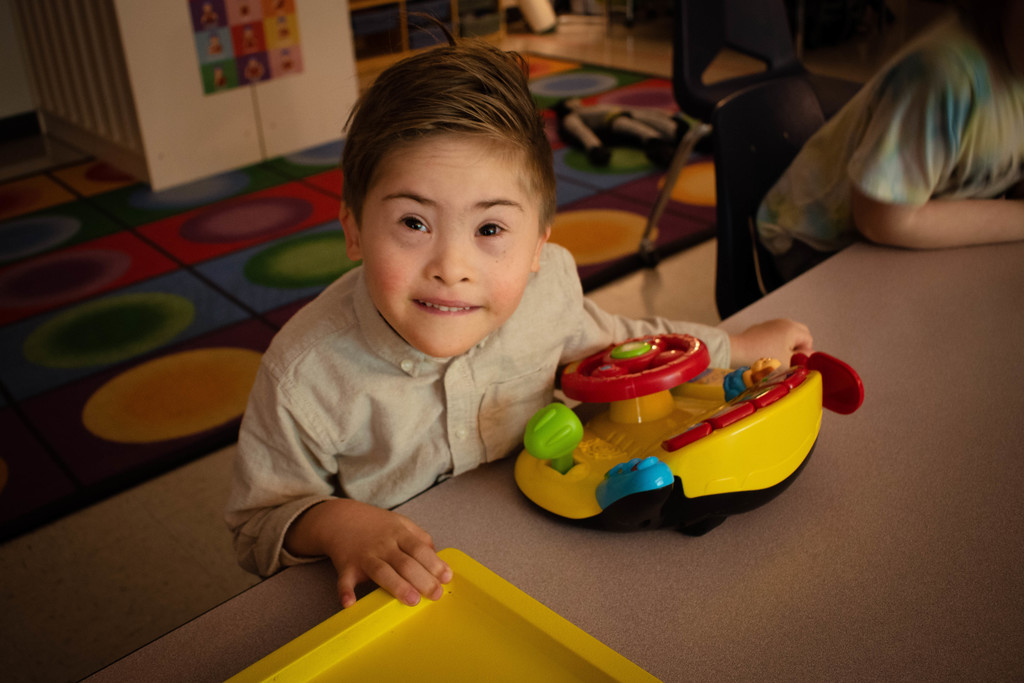 Student plays with toy and smiling at camera