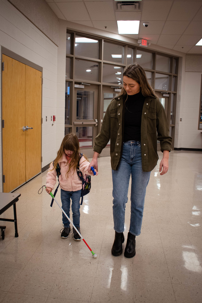 Ms. Holder walks with a student in the cafeteria.