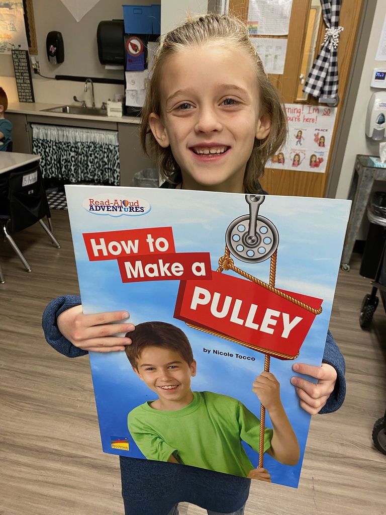 Student holds up a book called How to Make a Pulley