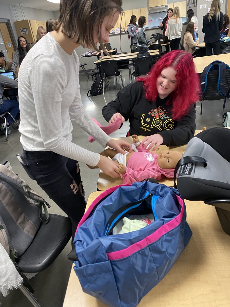 students changing baby doll's diaper