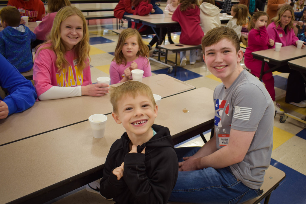 8th grade students and Kindergarten students smiling for camera