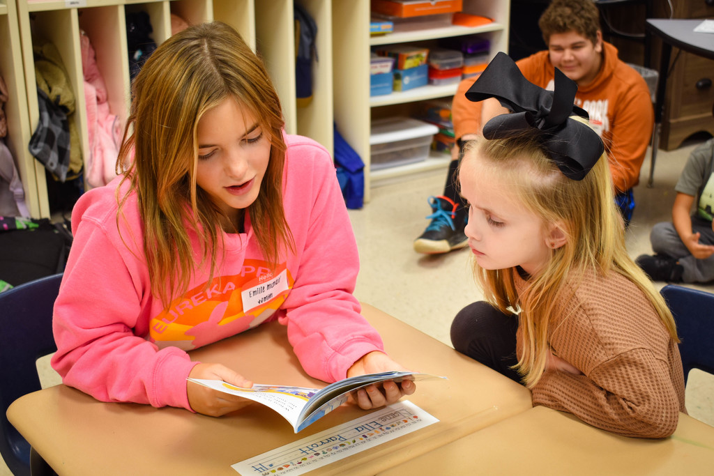 8th grade student reads to a Kindergarten student