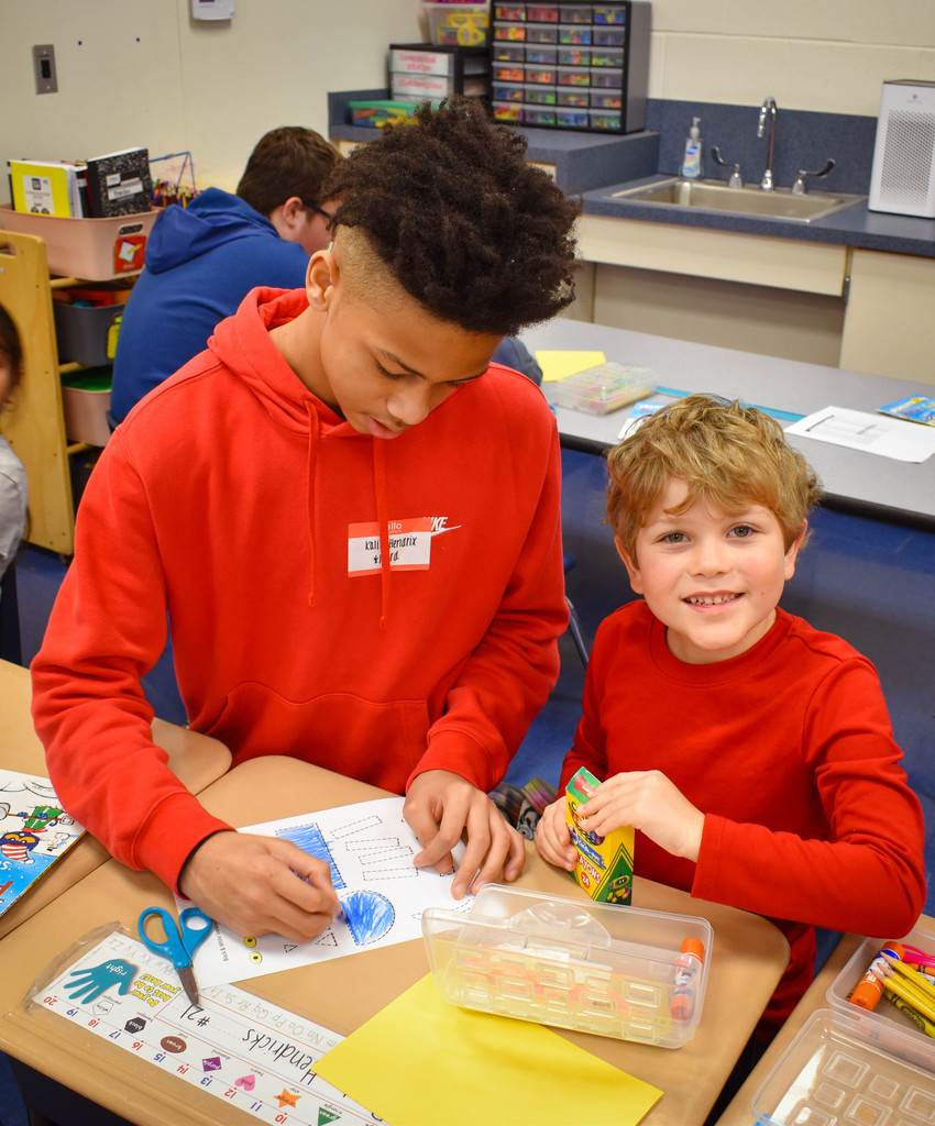 8th grade student does craft with a Kindergarten student