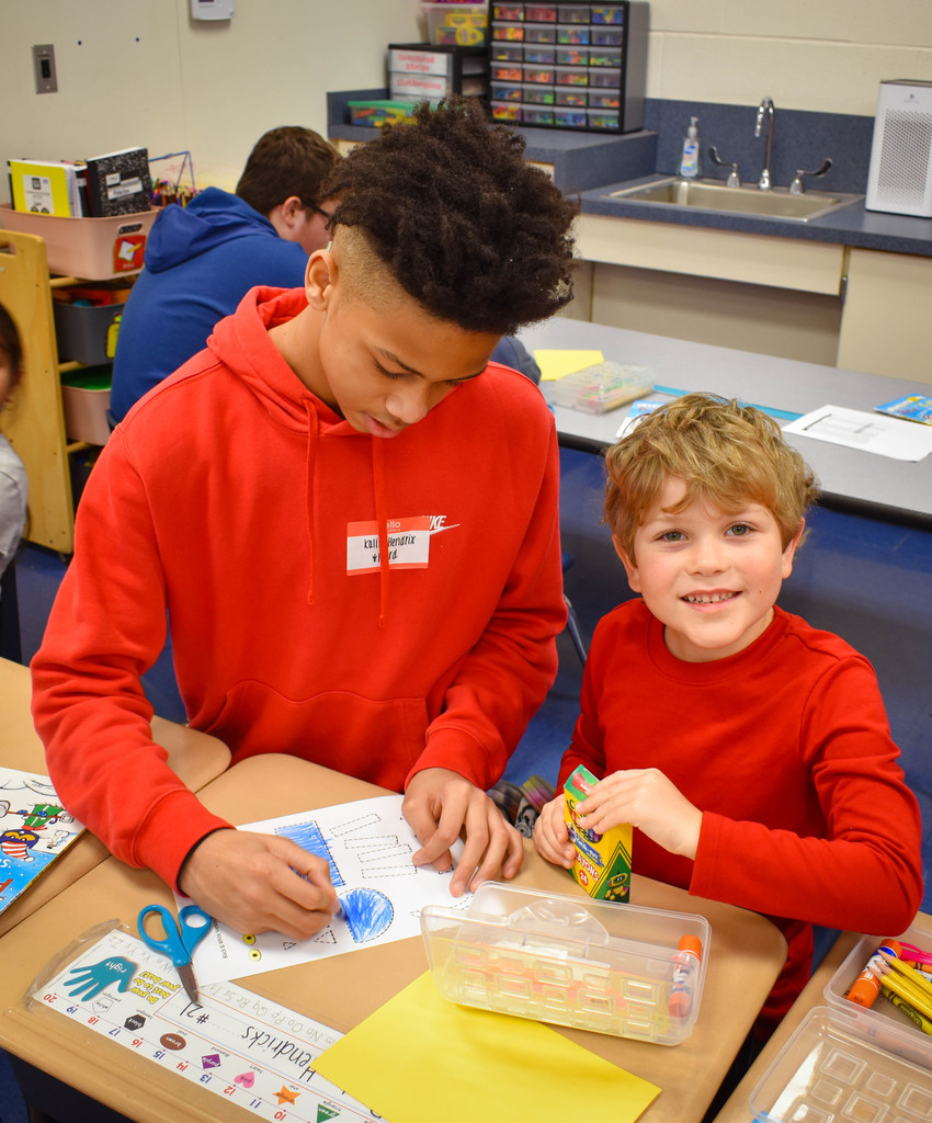 8th grade student does craft with a Kindergarten student