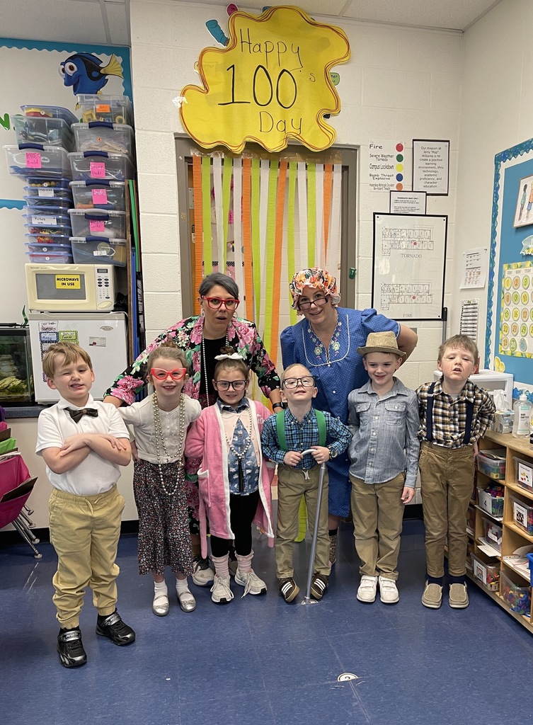 2 Grannies pose with students dressed up for 100th day of school
