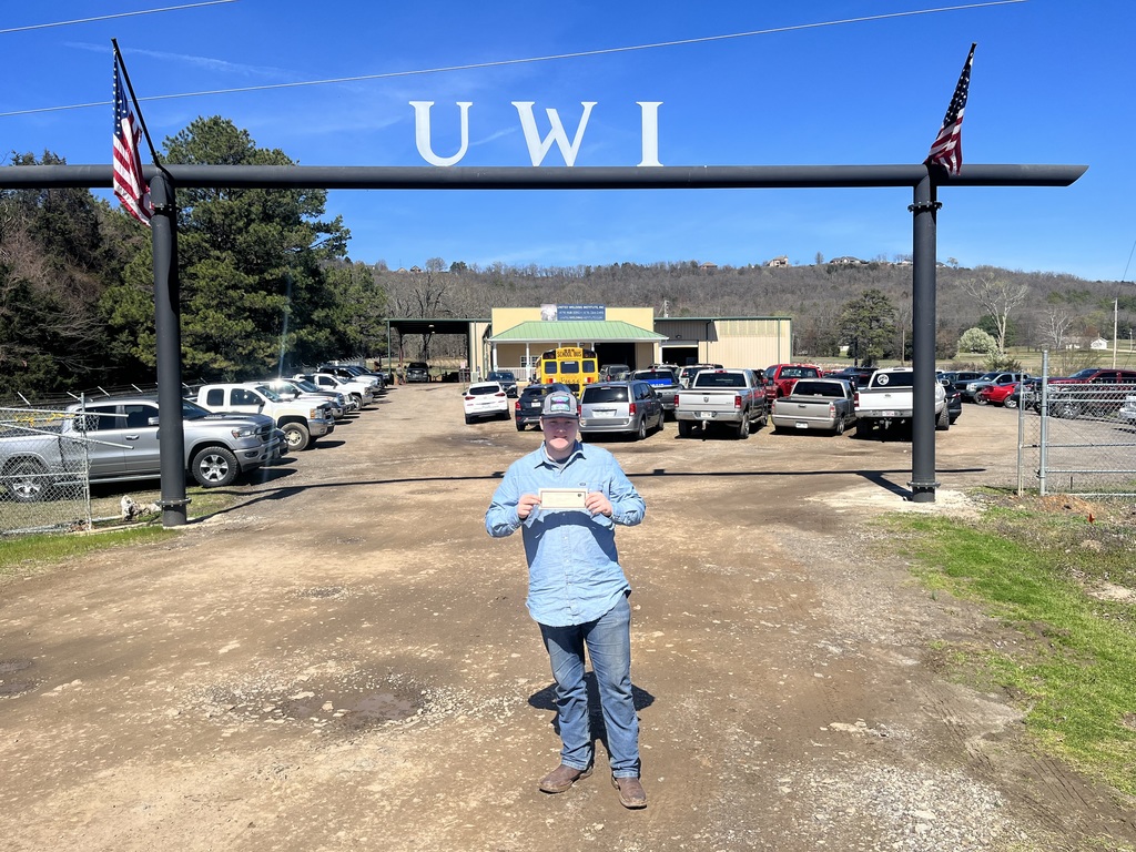 student standing outside welding school holding check