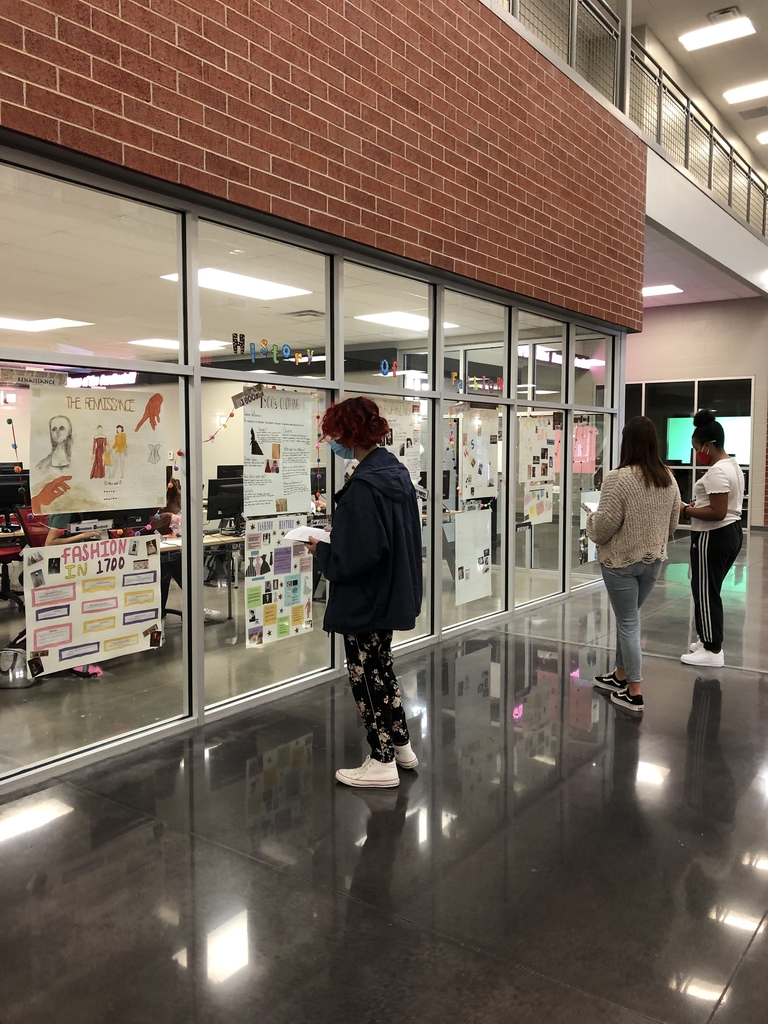 Students reading posters about fashion and taking notes